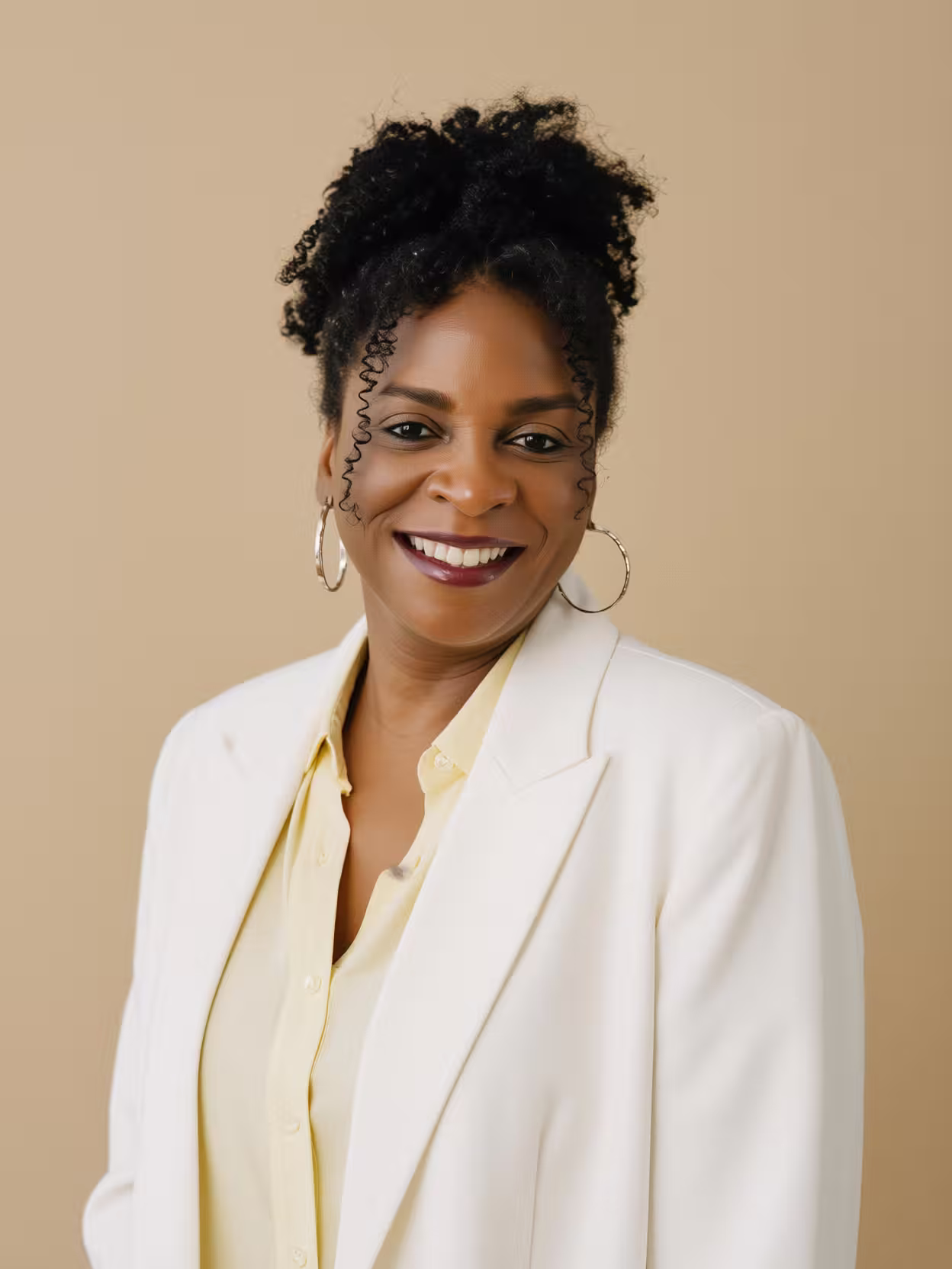 Leonie Noble-Dawkins, founder of Mane Glow Curls Specialist, wearing a professional business suit for her bio photo. Confident pose with her natural curly hair styled and defined.